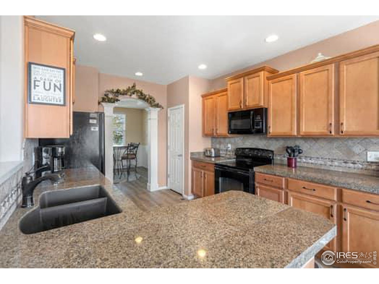 1545 Edenbridge Drive Windsor, CO 80550 - Photo 6 of 28 a kitchen with kitchen island granite countertop a stove top oven a sink a dining table and chairs