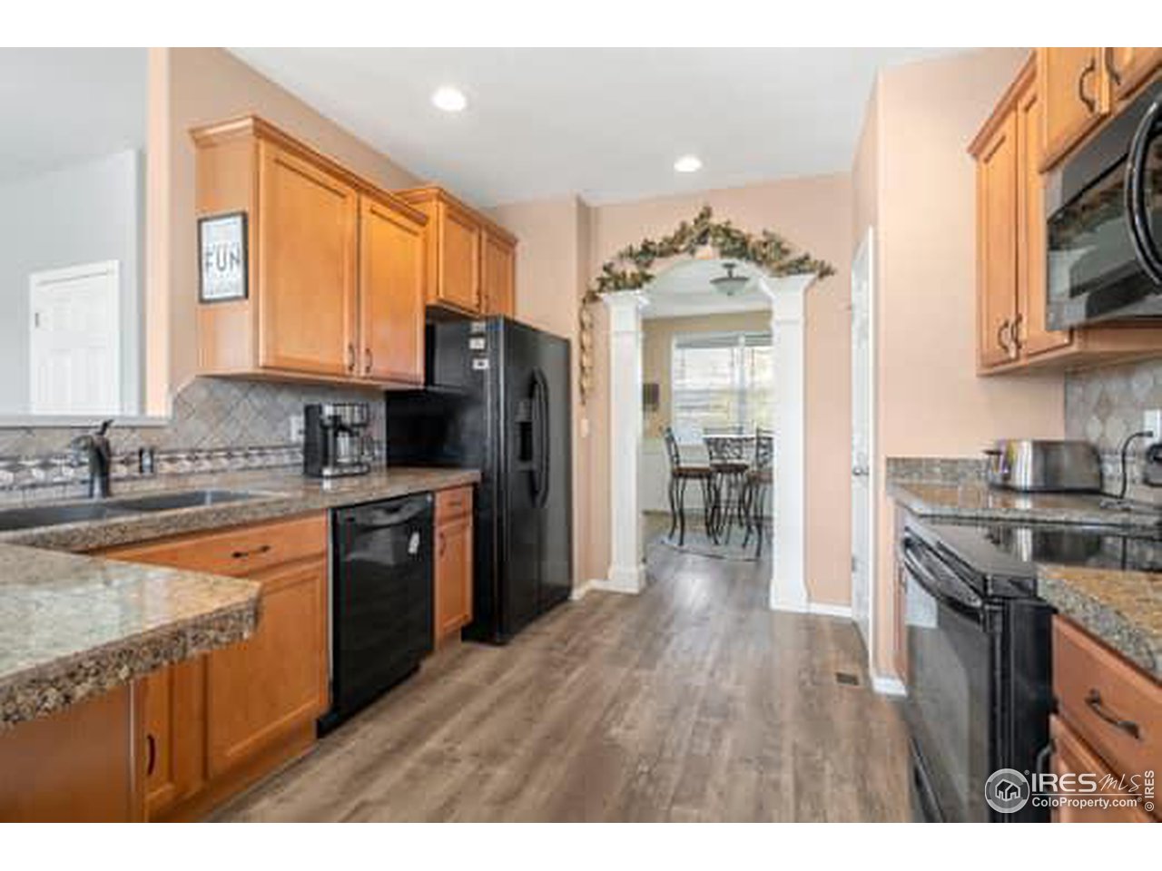 1545 Edenbridge Drive Windsor, CO 80550 - Photo 8 of 28 a kitchen with stainless steel appliances granite countertop a refrigerator a stove top oven a sink dishwasher and wooden cabinets with wooden floor