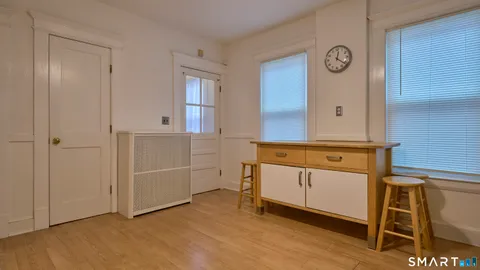 a view of a hallway with wooden floor and a bathroom