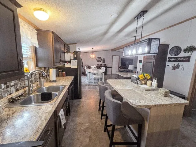 a kitchen with granite countertop a sink a counter space appliances and cabinets