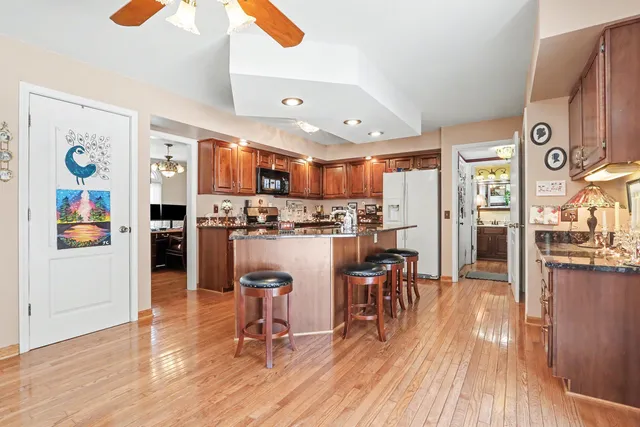 a living room with stainless steel appliances furniture wooden floor and a kitchen view
