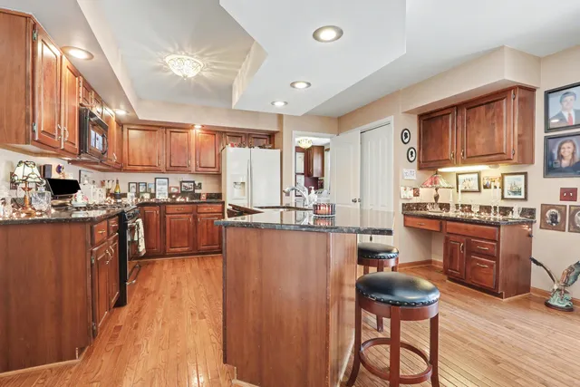 a kitchen with stainless steel appliances wooden cabinets a stove a sink dishwasher and a refrigerator with wooden floor