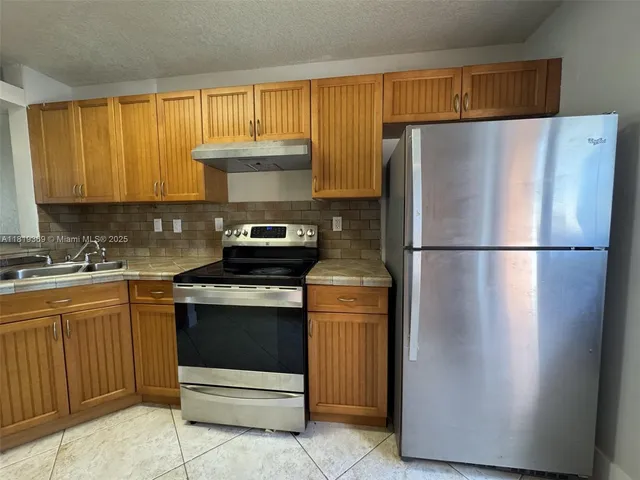 a kitchen with a refrigerator sink and cabinets