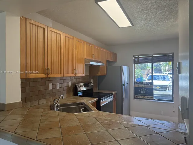 a kitchen with granite countertop a stove a sink and a refrigerator