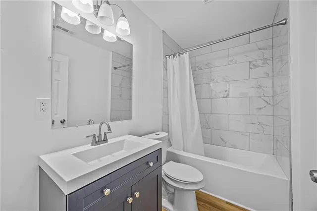 a bathroom with a sink a toilet a mirror and shower