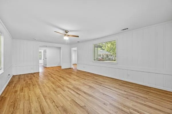 a view of empty room with wooden floor and fan