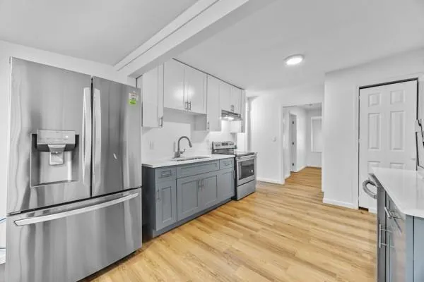a large kitchen with a refrigerator and wooden cabinets