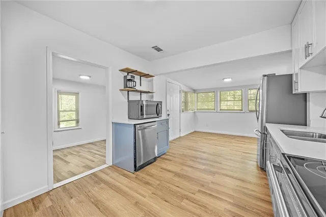a view of kitchen and empty room with wooden floor