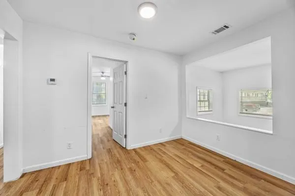an empty room with wooden floor and windows