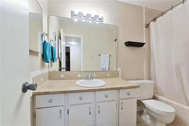 a bathroom with a granite countertop sink toilet a mirror a vanity and shower