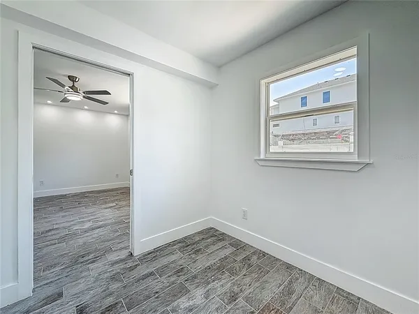 a view of an empty room with wooden floor and a window