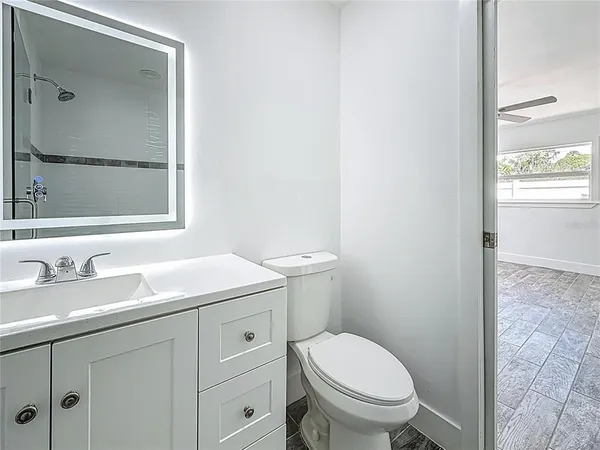 a bathroom with a granite countertop toilet sink and mirror