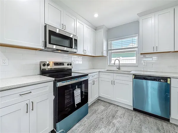 a kitchen with stainless steel appliances granite countertop a sink a stove a microwave and wooden cabinets