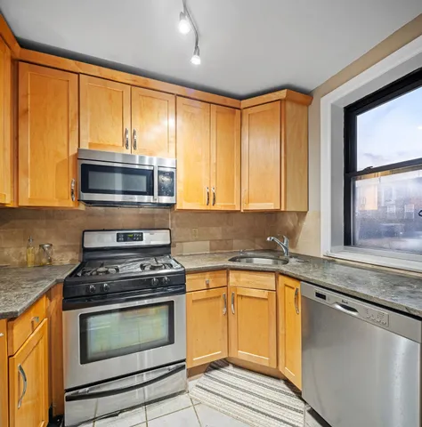 a kitchen with granite countertop cabinets stainless steel appliances and window