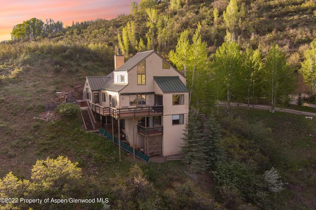 a view of a house with a small yard and large trees