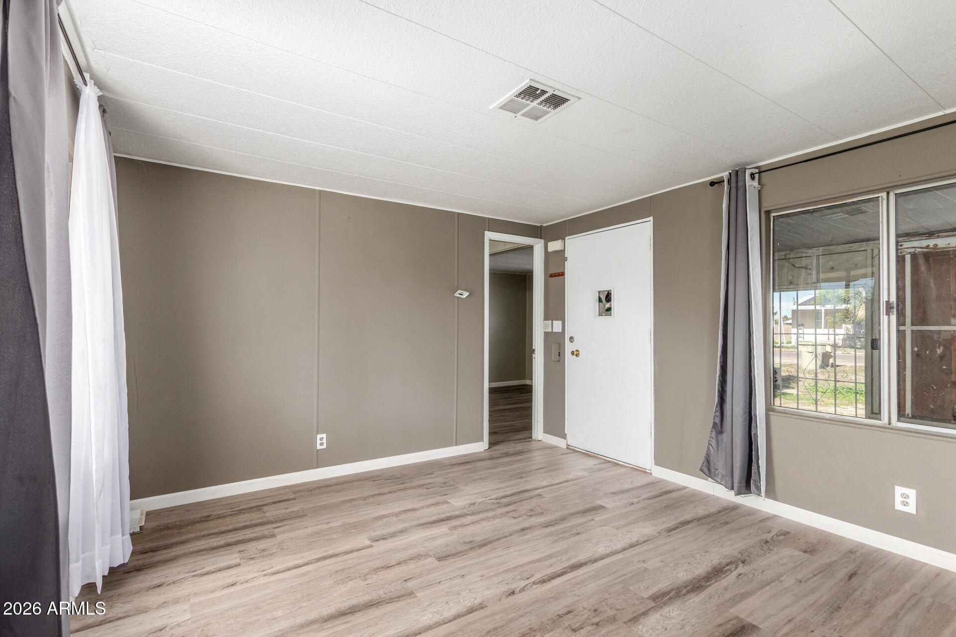 6633 West Nancy Road Glendale, AZ 85306 - Photo 4 of 29 a view of an empty room with wooden floor and a window