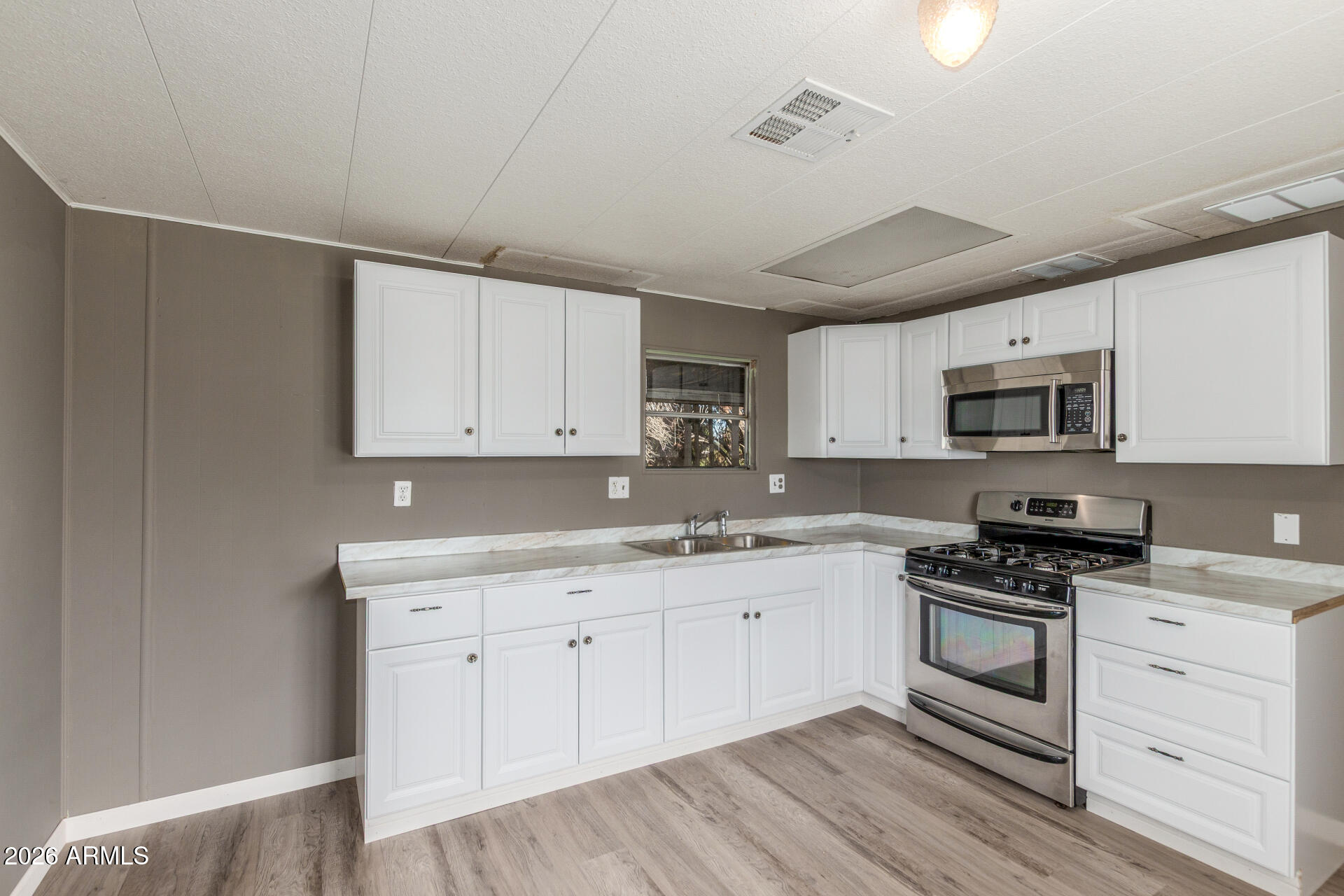6633 West Nancy Road Glendale, AZ 85306 - Photo 8 of 29 a kitchen with granite countertop white cabinets white stainless steel appliances with a sink and dishwasher