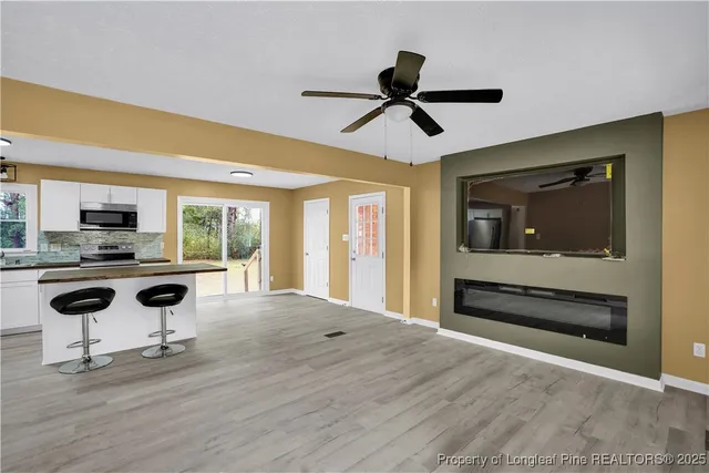 a view of a livingroom with kitchen appliances and wooden floor
