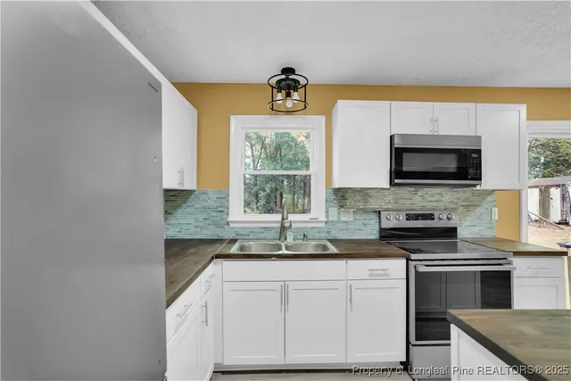 a kitchen with granite countertop a stove a sink and a microwave