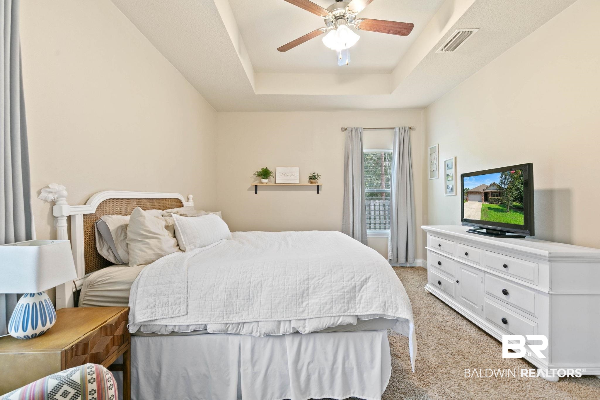 2216 Livingstone Court Mobile, AL 36695 - Photo 22 of 62 Bedroom featuring a tray ceiling with a ceiling fan, neutral wall paint, and a window with light-toned curtains