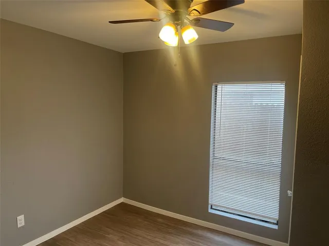 an empty room with wooden floor closet and windows
