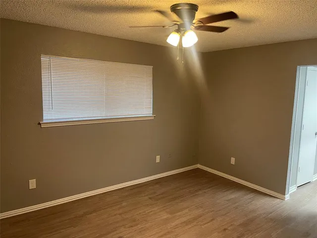 an empty room with a window and a fan