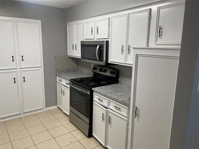 a kitchen with white cabinets and appliances