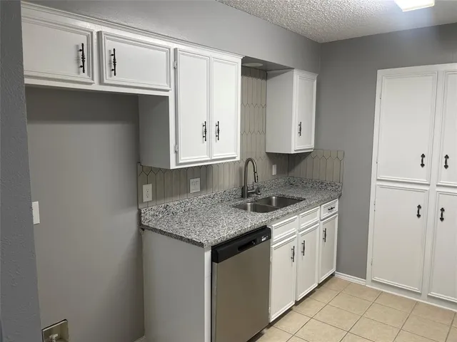 a kitchen with stainless steel appliances granite countertop a sink and dishwasher with white cabinets