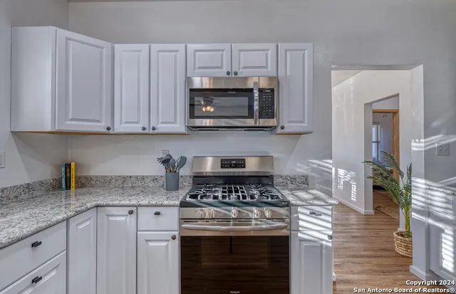 a kitchen with granite countertop white cabinets and stainless steel appliances