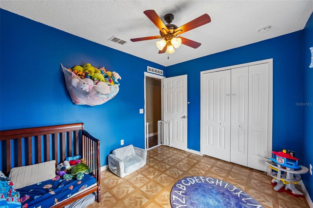 10303 Fordham Street Spring Hill, FL 34608 - Photo 15 of 25 a bedroom with a bed and a chandelier