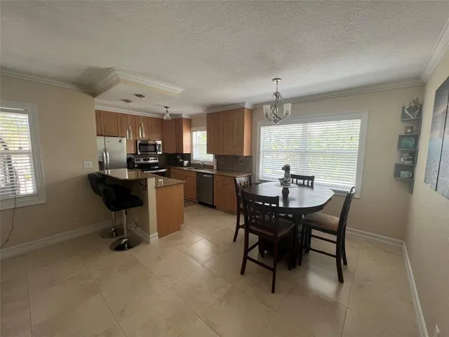 a kitchen with a dining table chairs and refrigerator
