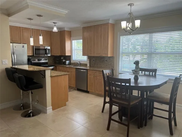 a kitchen with stainless steel appliances granite countertop a sink a stove a refrigerator a dining table and chairs