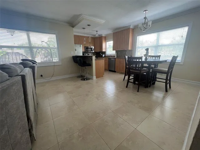 a kitchen with stainless steel appliances kitchen island granite countertop dining table chair and a window