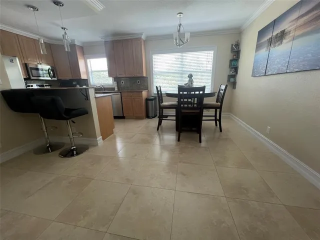 a kitchen with stainless steel appliances kitchen island granite countertop dining table chair and a refrigerator