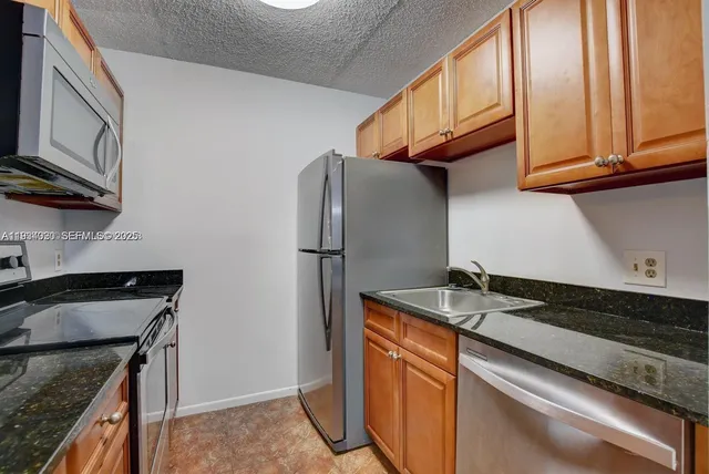 a kitchen with stainless steel appliances granite countertop a refrigerator a stove and a sink