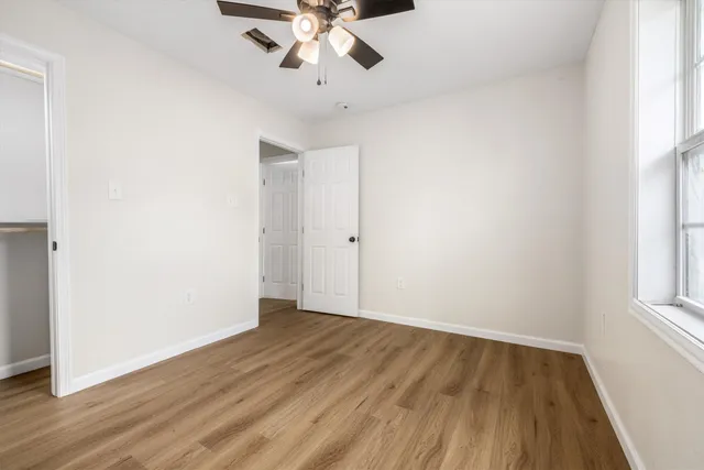 an empty room with wooden floor and windows
