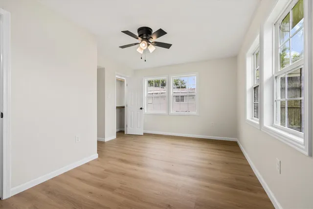 a view of an empty room with a window and wooden floor