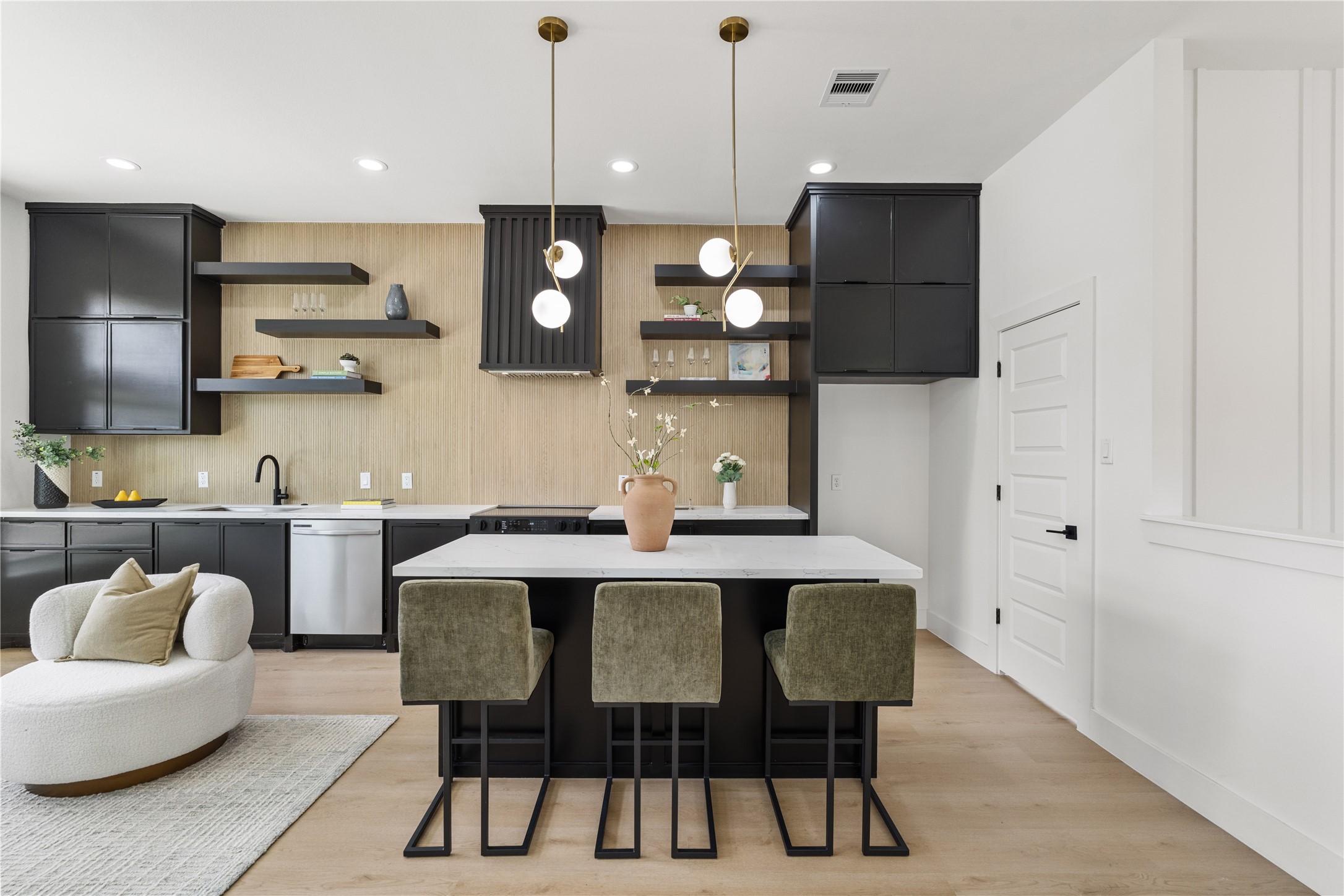 7319 Laura Koppe Road Houston, TX 77028 - Photo 5 of 42 Sleek modern kitchen featuring a large island with stylish pendant lighting, open shelving, and elegant black cabinetry for a chic and functional space.