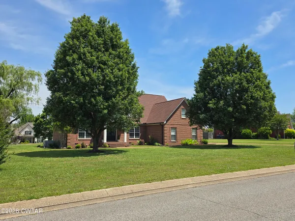a view of a white house with a big yard and large trees