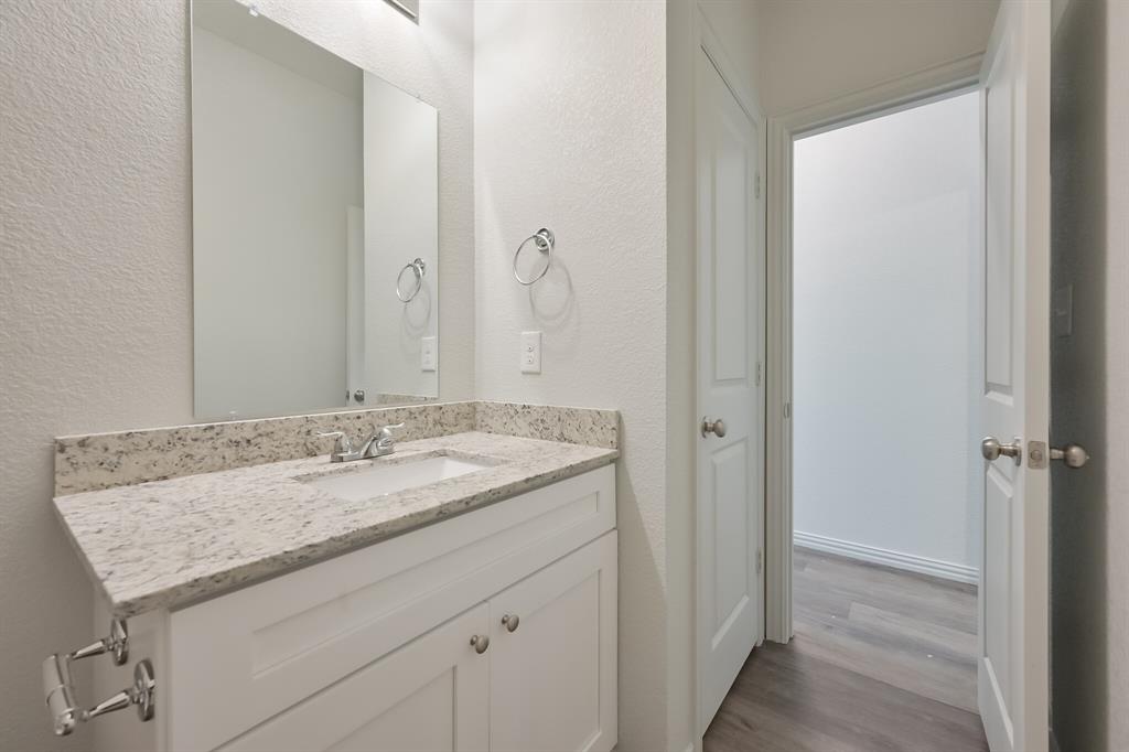 1716 East Powell Avenue Fort Worth, TX 76104 - Photo 3 of 13 a bathroom with a granite countertop sink and a mirror