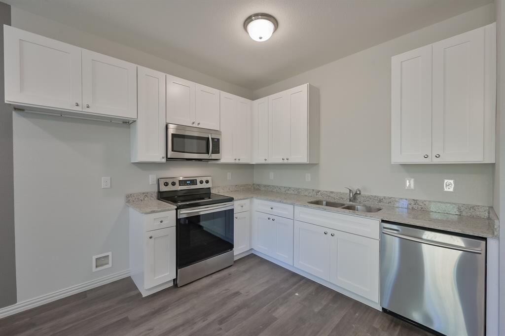 1716 East Powell Avenue Fort Worth, TX 76104 - Photo 5 of 13 a kitchen with granite countertop white cabinets stainless steel appliances and a sink