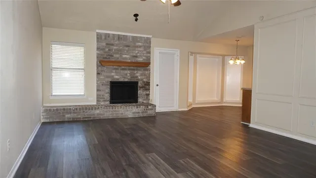 an empty room with wooden floor fireplace and windows