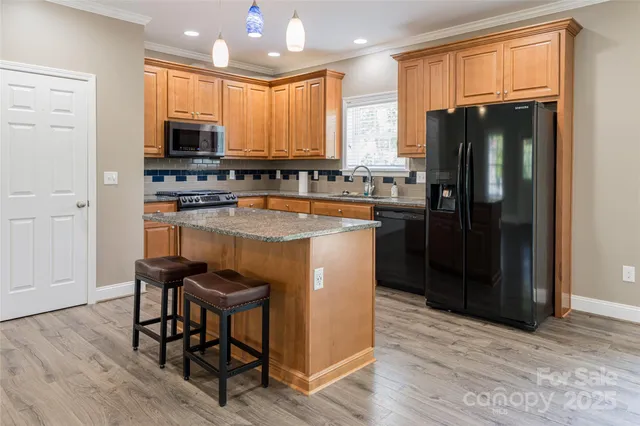 a kitchen with stainless steel appliances granite countertop a refrigerator a stove top oven a sink dishwasher and wooden floor