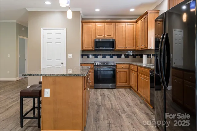 a kitchen with stainless steel appliances granite countertop a stove top oven a sink and a refrigerator