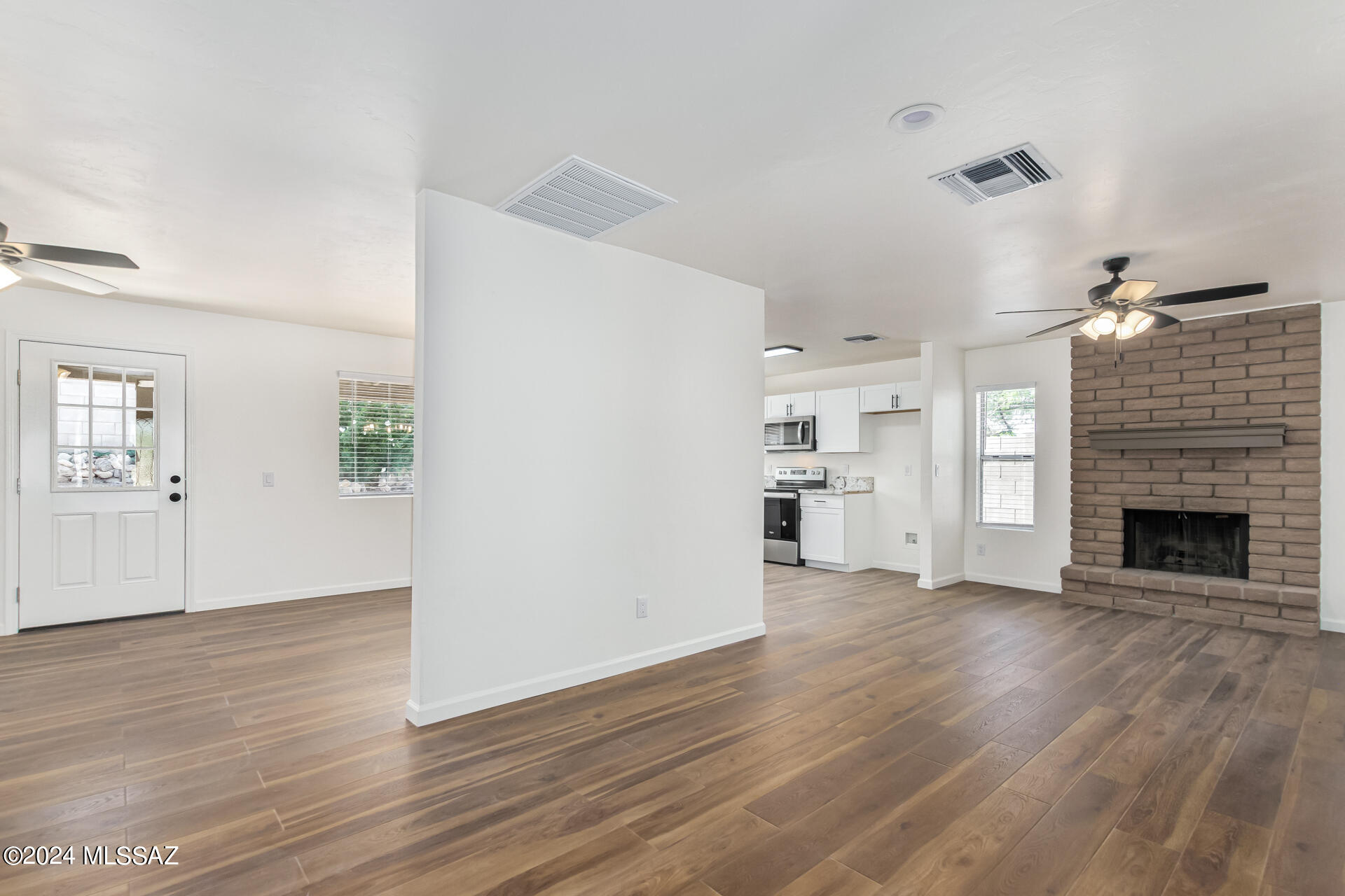 1454 South Gecko Road Tucson, AZ 85713 - Photo 10 of 24 an empty room with wooden floor fireplace and windows
