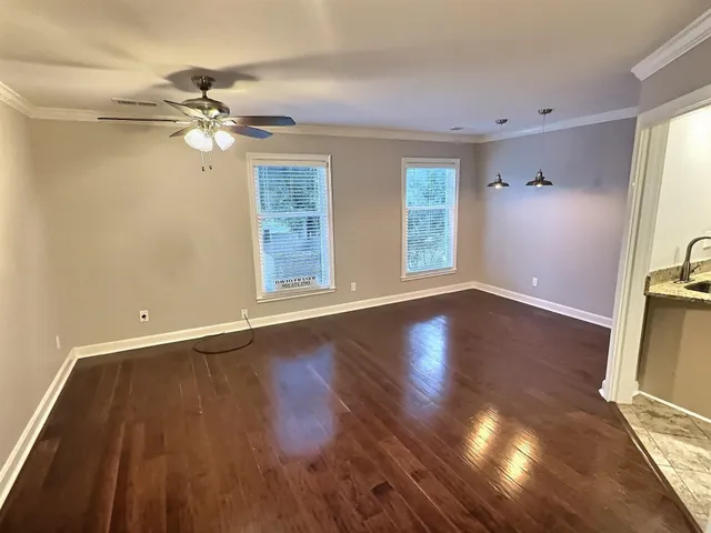 a view of an empty room with wooden floor and a window