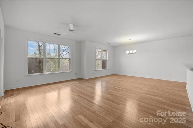 a view of kitchen and empty room with wooden floor
