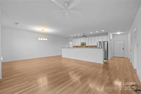 a view of kitchen and empty room with wooden floor
