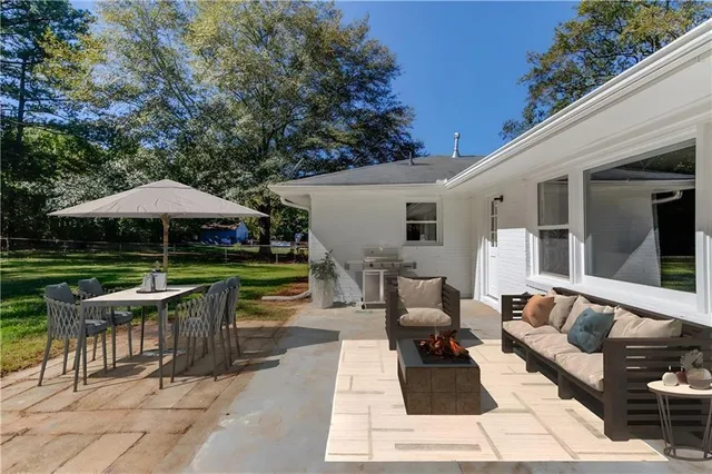 a view of a patio with a table and chairs under an umbrella with a barbeque