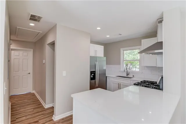 a kitchen with a refrigerator a sink and wooden floor
